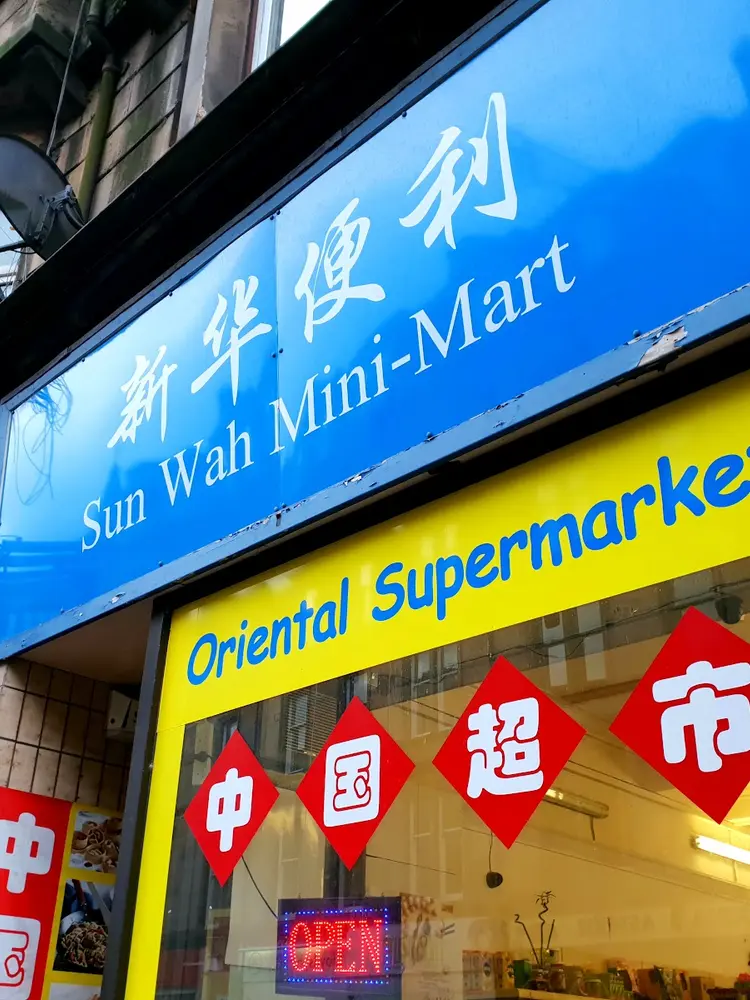 Sun Wah Mini-Mart's blue shop sign in Chinese and English above a yellow shopfront